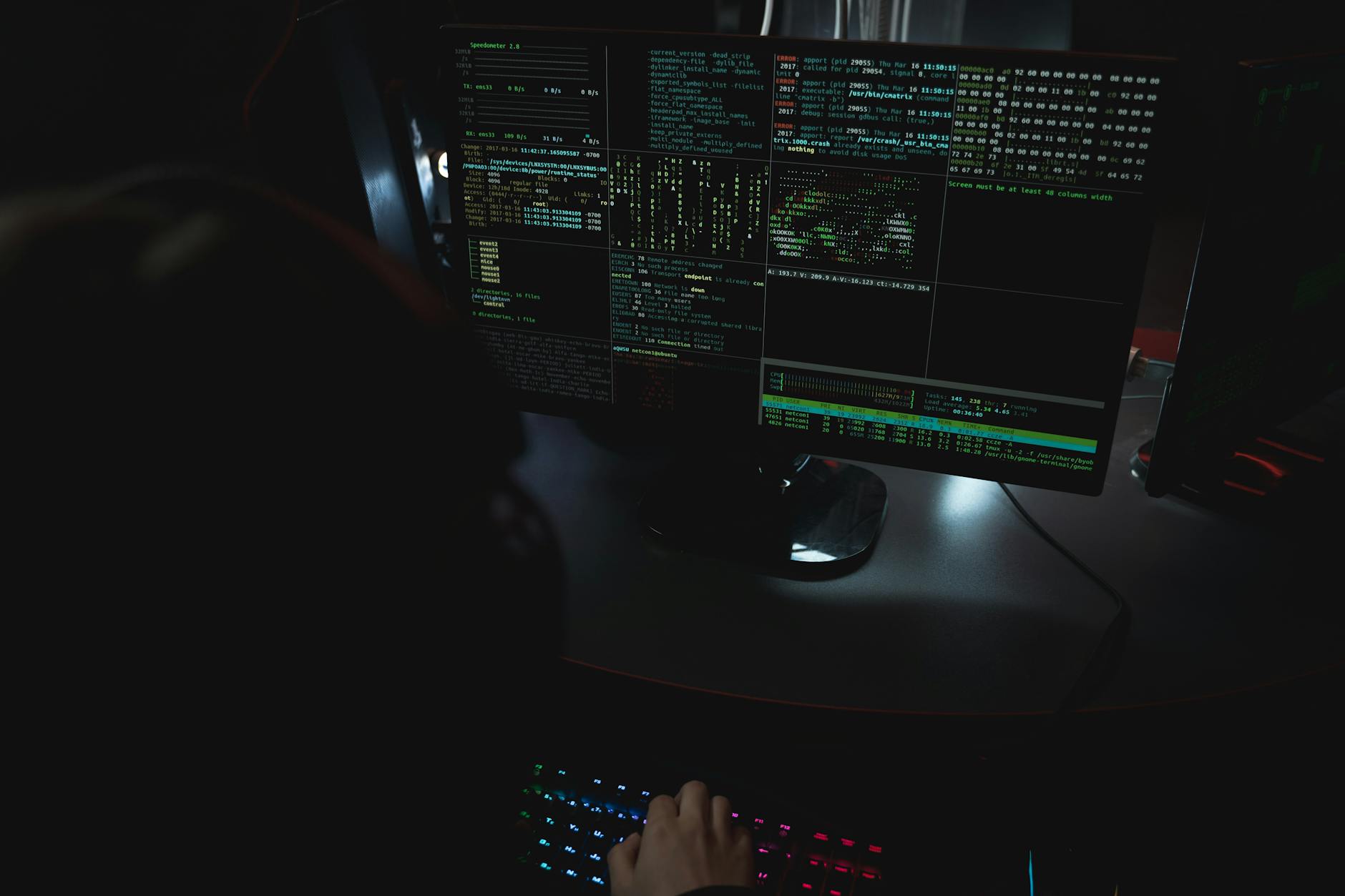 Monitory z kodem w ciemnym pokoju ilustrujące cyberbezpieczeństwo