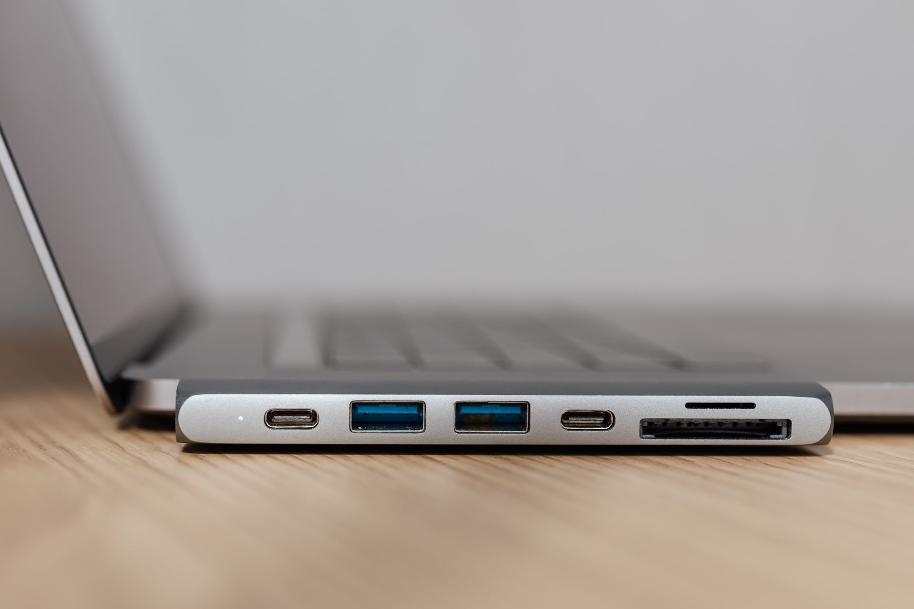 Szary hub USB‑C z wieloma portami podłączony do laptopa
