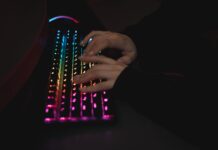 Dłonie piszące na mechanicznej klawiaturze RGB w ciemnym otoczeniu