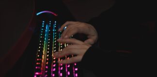 Dłonie piszące na mechanicznej klawiaturze RGB w ciemnym otoczeniu