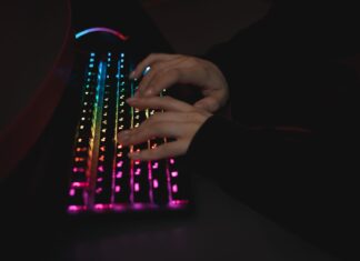Najlepsze klawiatury mechaniczne do pisania kodu – porównanie przełączników i ergonomii Dłonie piszące na mechanicznej klawiaturze RGB w ciemnym otoczeniu