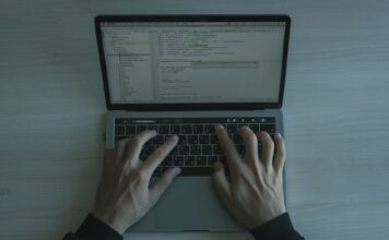 Bezpieczeństwo w świecie frameworków JS: konfiguracje, biblioteki ochronne i dobre praktyki DevSecOps Programista piszący kod zabezpieczeń JS na nowoczesnym laptopie