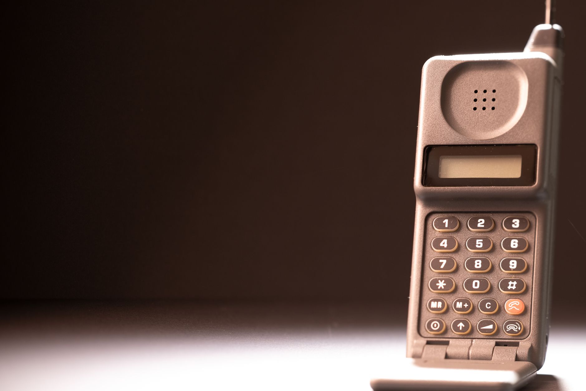 Stary telefon komórkowy z klawiaturą i anteną na ciemnym tle